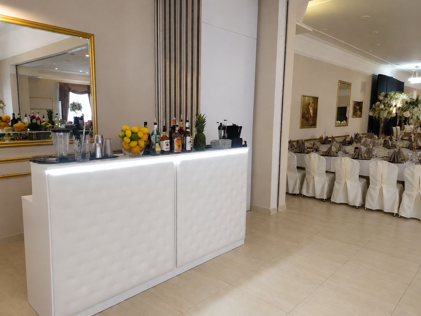 Elegancki biały mobilny bar Aurum z owocami i alkoholami na sali weselnej